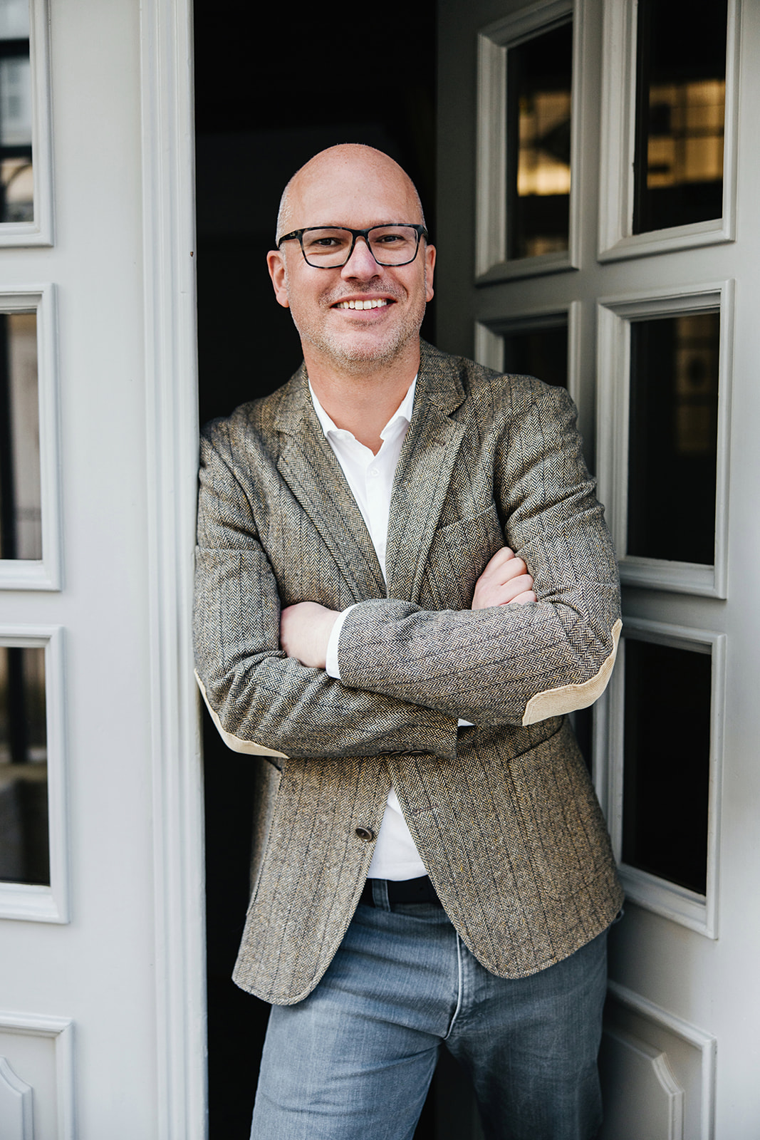 Immobiliengutachter steht selbstbewusst im T&uuml;rrahmen eines Geb&auml;udes und vermittelt Vertrauen und fachliche Kompetenz.